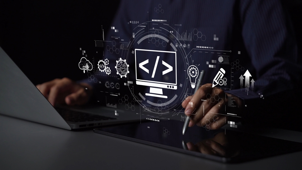 Developer at a laptop and tablet with a code symbol projected above the desk